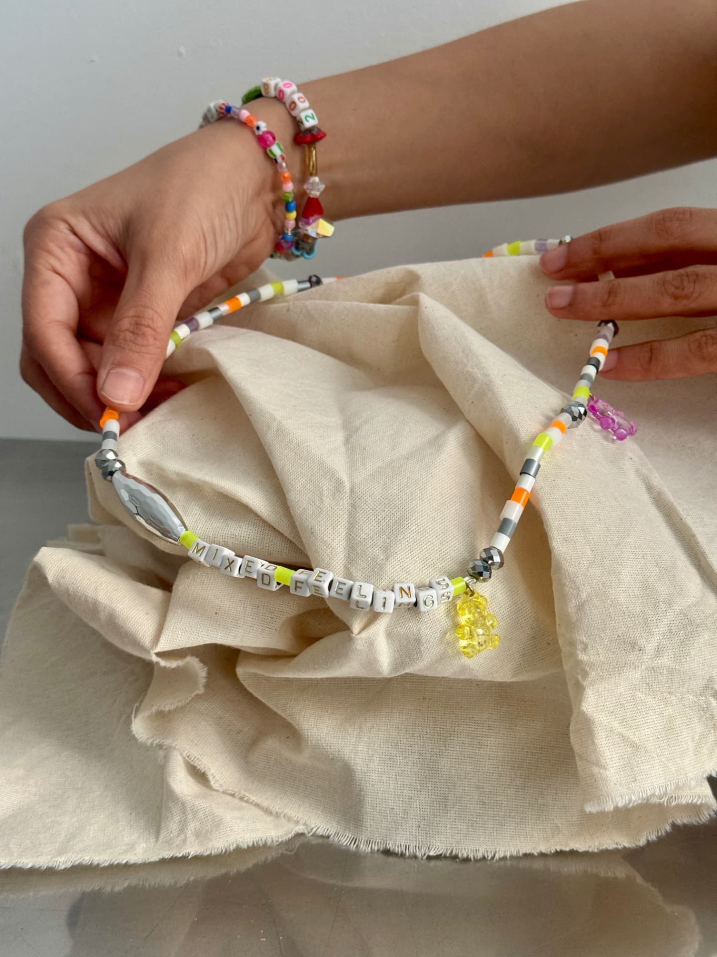 A finished beaded necklace draped over cream fabric