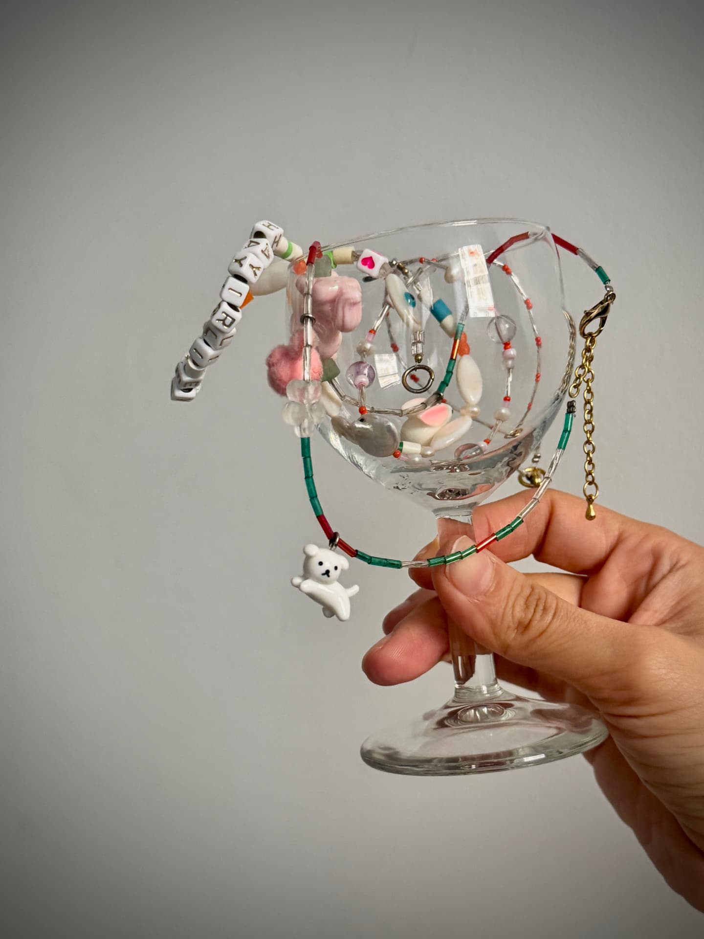 Beaded necklaces draped over a wine glass, with a little white bear charm