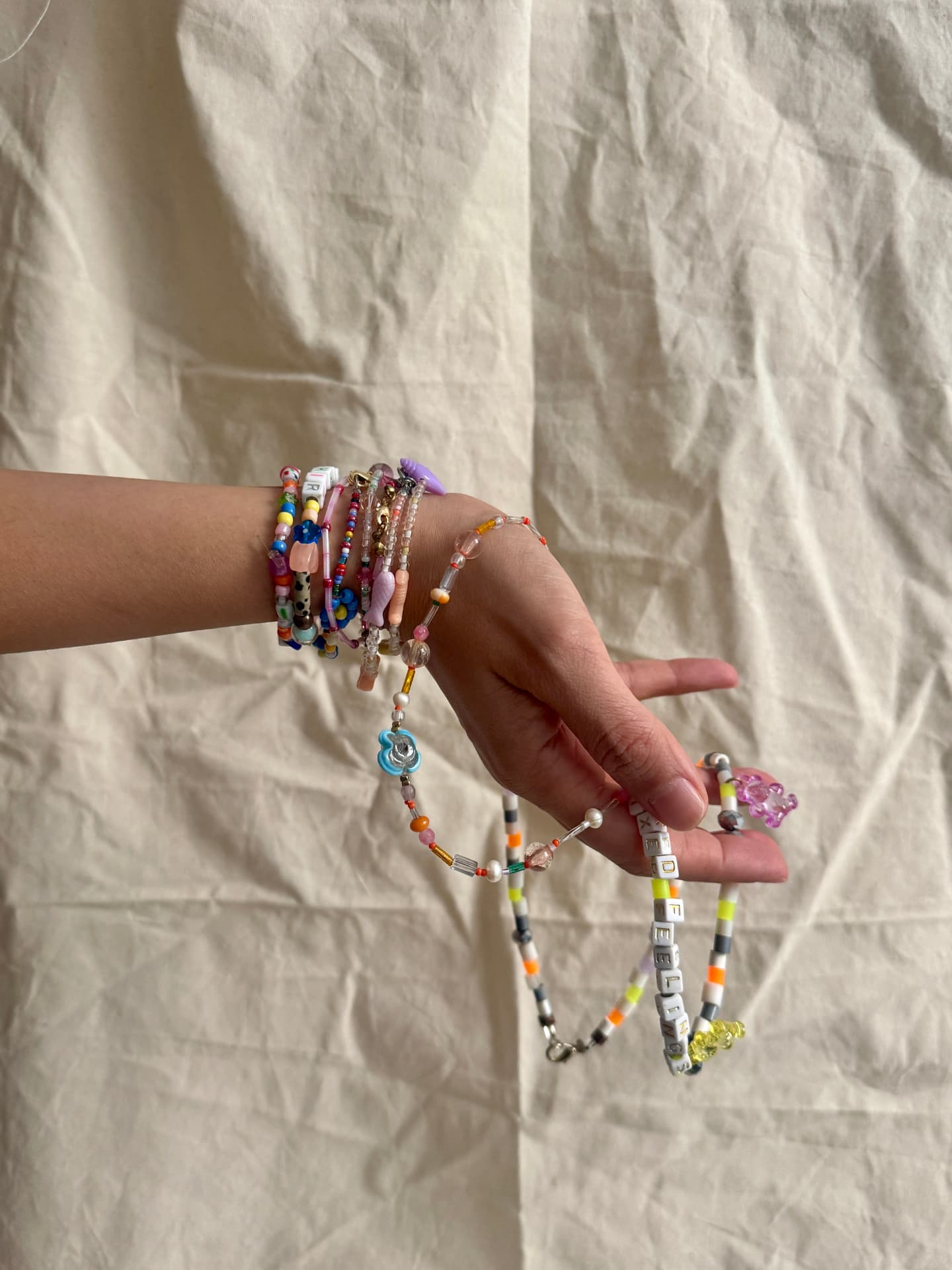 An arm stacked with beaded bracelets and necklaces